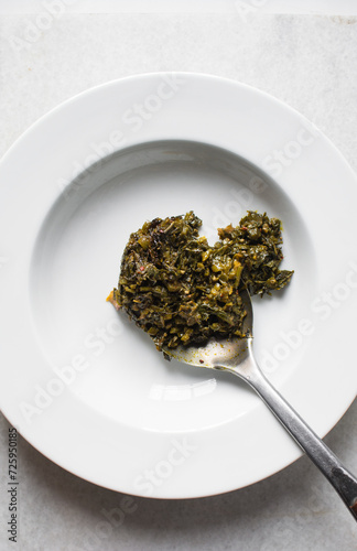 Nigerian vegetable soup with fish and bush meat in a white plate, afang soup in a large dinner plate, traditional edikang ikong soup in a white dish photo