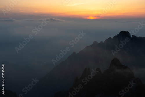A golden sun sinks below the horizon in the White Cloud Scenic Area as viewed from Turtle Peak in Huangshan Yellow Mountains.