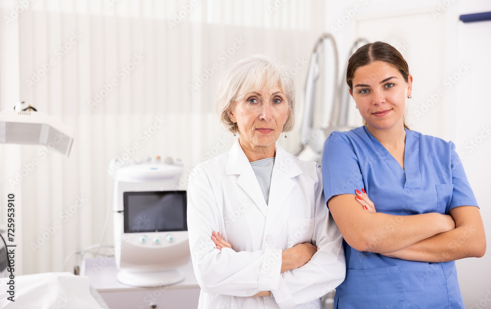 Obraz premium Confident senior woman cosmetologist and her assistant nurse looking at camera in clinic of aesthetic medicine
