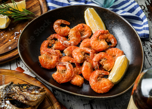 Fried shrimps or prawns with lemon slices on plate over wooden rustic background. Seafood, healthy food, top view