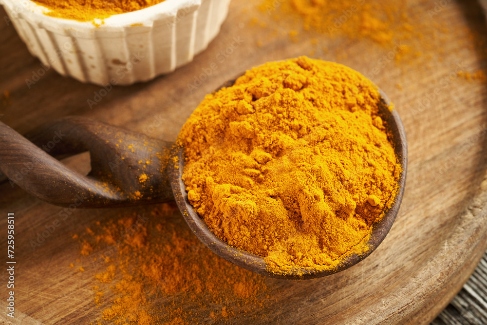 Ground turmeric root on a spoon on a table Ground turmeric root on a spoon on a table
