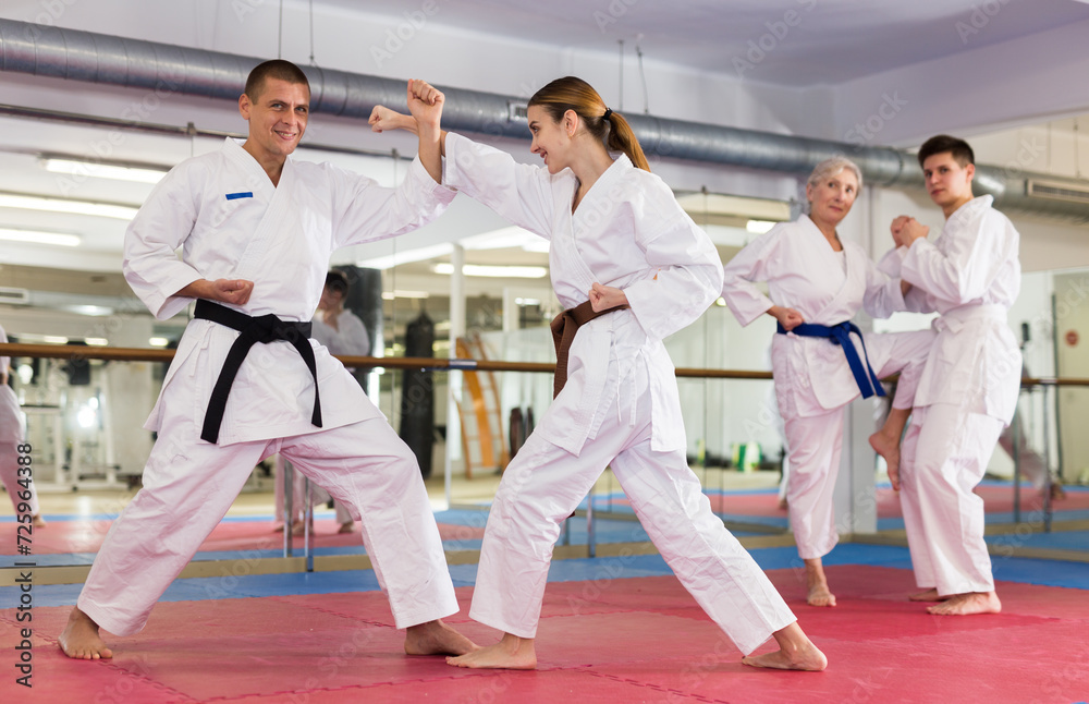 Man and woman in kimono sparring together in gym during karate training