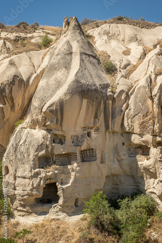 Typical stone dwelling carved in the fairy chimneys with dovecotes carved in the volcanic rock, rock hoodoo in Goreme, Cappadocia, Turkey, vertical photo