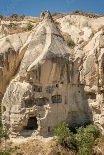 Typical stone dwelling carved in the fairy chimneys with dovecotes carved in the volcanic rock, rock hoodoo in Goreme, Cappadocia, Turkey, vertical