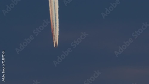 Jet leaving colorful contrails in the dusk sky