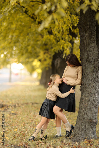 Family day. Young mom and little daughter having fun and enjoy relaxing outdoors in autumn park. Adorable child girl tightly hugs and kiss her mother. Maternal care and love for kid. Mothers day