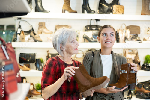 Elderly female friend strongly recommends her young colleague to pay attention to contemporary model of chelsi boots made in light leather