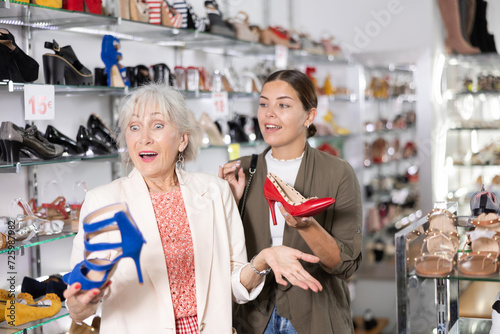 Mom and daughter are picking up open summer shoes for party.In store,cheerful female friends choose elegant spike heels or high heel sandals