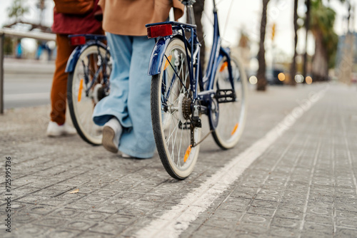 Fototapeta Naklejka Na Ścianę i Meble -  Cropped picture of friends pushing bikes on the street.