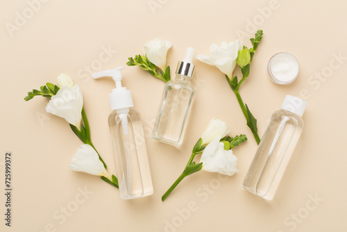 Facial cosmetic products with freesia flowers on color background  top view