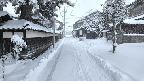 Walking narrow snow covered road by traditional Japanese houses in small village