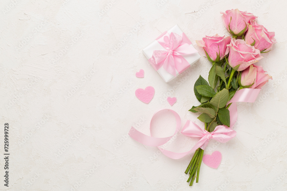 Pink roses with hearts and gift box on concrete background, top view. Valentines day concept