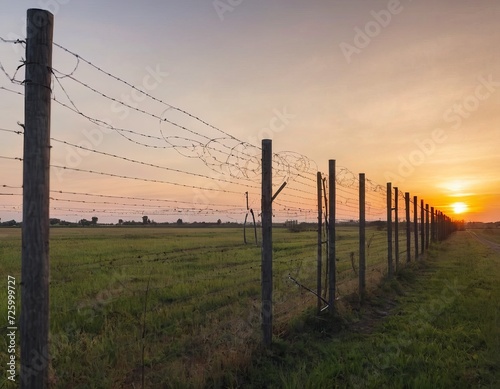 Barbed wire fence against a sunset background. To illustrate articles and materials related to restricted access, security, borders, military bases or prisons.