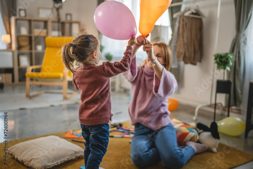 mother and daughter toddler girl play with balloons family bonding