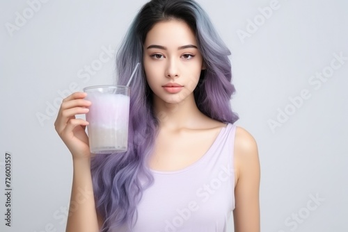 portrait on a white background A girl with purple hair of Asian appearance drinks a collagen drink. skin care, moisturizing. Supplements.