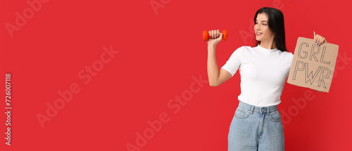 Young woman holding dumbbell and paper with slogan GRL PWR on red background with space for text. Feminism concept photo