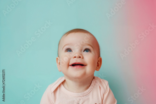 Slika na platnu Smiling baby-girl looking upwards against a pastel-coloured background