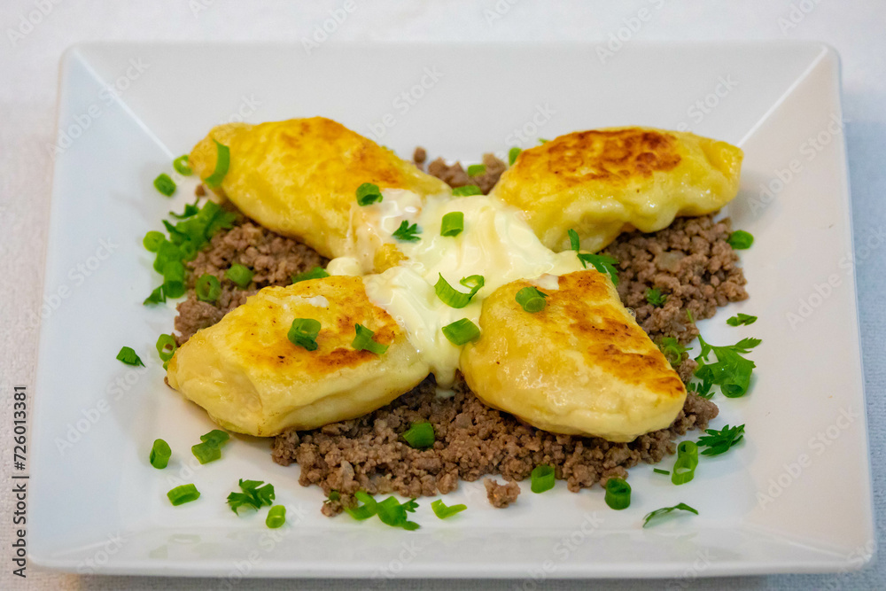 Traditional Ukrainian pierogi grilled in butter and served with minced meat and cream, decorated with fresh fine herbs Traditional Ukrainian pierogi grilled in butter and served with minced meat and cream, decorated with fresh fine herbs