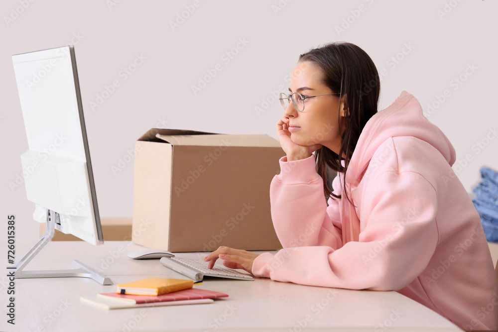 Female seller working with computer at table in warehouse store Female seller working with computer at table in warehouse store