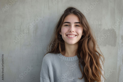 A woman wearing a grey sweater smiles for the camera