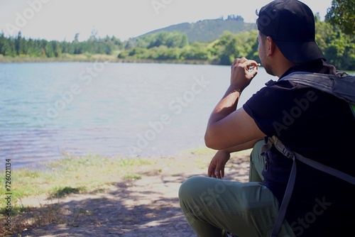 man smoking a cigarette on the shore of a lake
