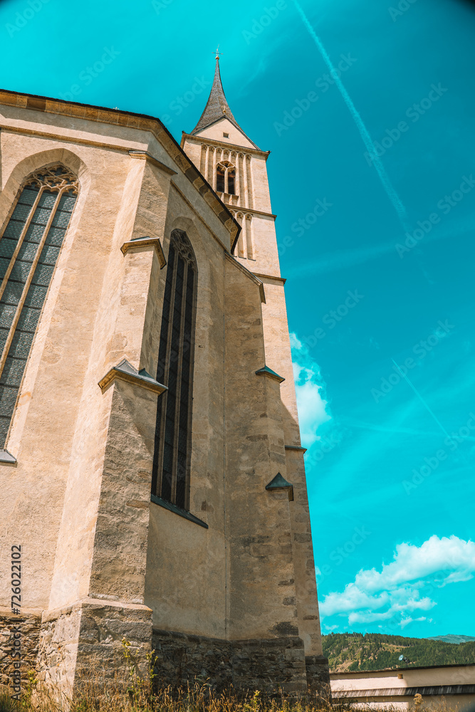 Church of St. Leonard in Austria on a bright blue sky background. Catholic Church architecture outside.Church building in Gothic style.Christian and catholic faith symbol.Religious symbol.