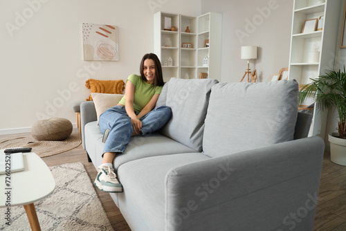 Young woman resting on grey sofa in living room