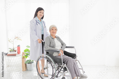 Asian health worker drive a wheelchair of old patient, doctor and old female talk about disease symptoms and treatment plan, happy hospital, rehabilitation activity, elderly healthcare promotion