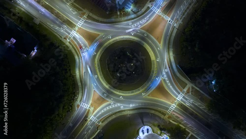 Aerial view of road roundabout intersection with fast moving heavy traffic at night. Timelapse of illuminated urban circular transportation crossroads photo
