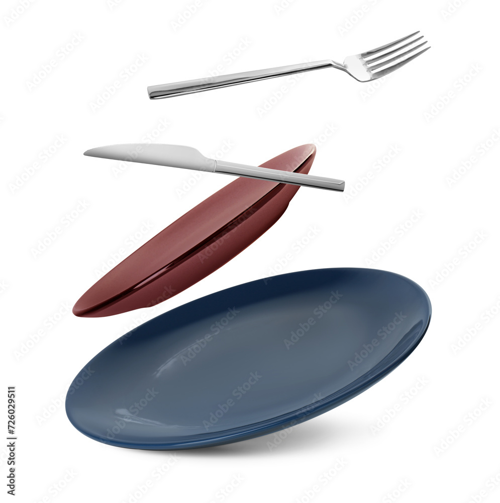 Clean plates, fork and knife falling on white background Clean plates, fork and knife falling on white background