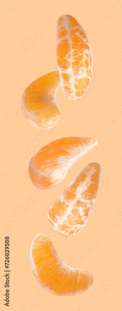Pieces of fresh ripe tangerine falling on pale orange background Pieces of fresh ripe tangerine falling on pale orange background