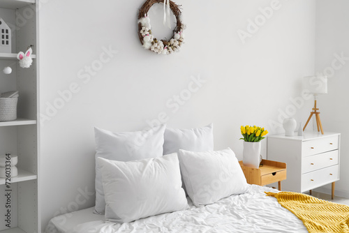 Interior of light bedroom with Easter wreath and tulips photo