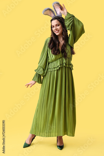 Beautiful woman in bunny ears on yellow background. Easter celebration