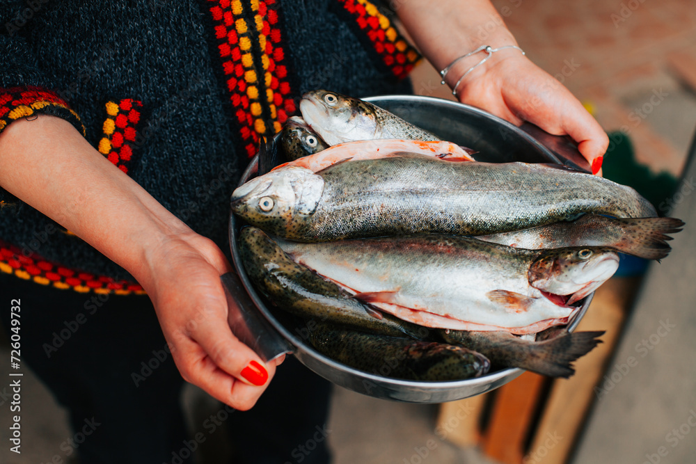 Photograph of anonymous hands with many trout in a bowl. Concept of food preparation.