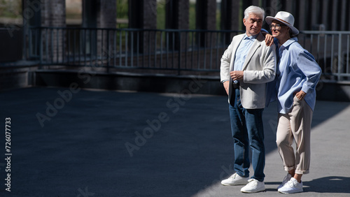 Stylish mature couple. Gray-haired man and woman holding hands while walking around the city. 