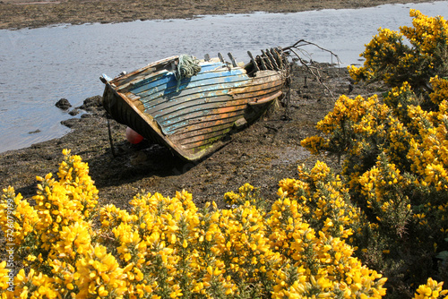 Colorful wrecked wooden rowboat on water bank, Glencolmcille, Ireland 