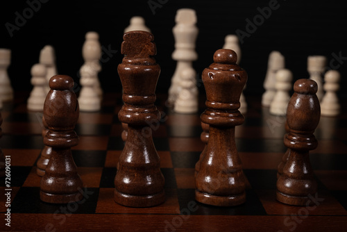 Close up of chess pieces on a chess board. King, queen, and bishop in the foreground.