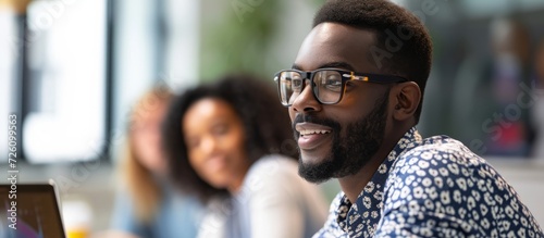 An African American man in glasses explains strategy ideas to his coworker in an office, while diverse partners brainstorm. photo