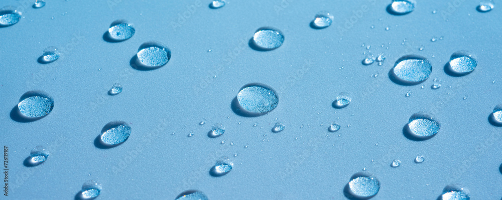Water background with drops on a blue surface, wet pattern. Spa concept, texture of cosmetics, gel, serum. Aqua spray, banner