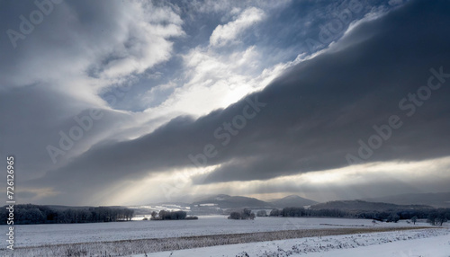 Fantastic winter landscape with snow covered field and dark stormy sky © Denis Sined