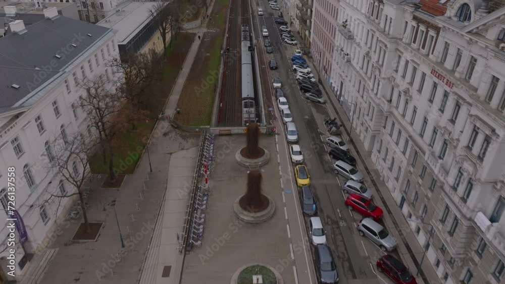 High angle view of railway infrastructure in city. Forwards tracking of train passing on line between buildings. Tilt up reveal aerial view of urban borough. Vienna, Austria