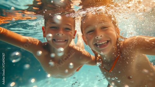 Photograph of siblings playing a game of tag underwater  with a burst of laughter and bubbles. 