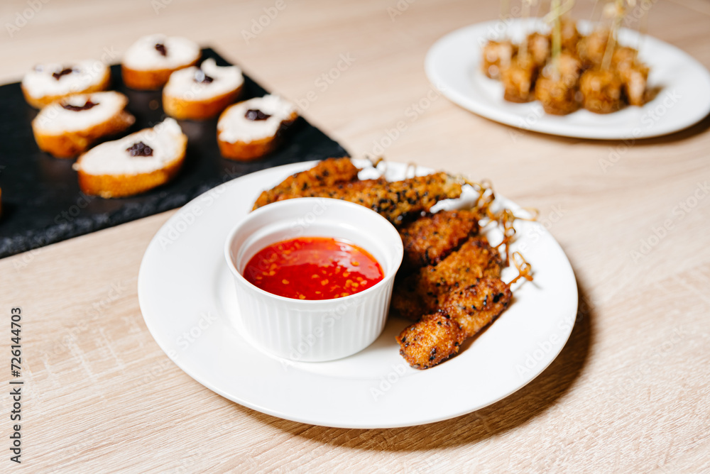 Crispy Chicken Tenders with Sweet Chili Dip. Golden-brown crispy chicken tenders served on a white plate with sweet chili sauce, perfect for a savory snack or appetizer.