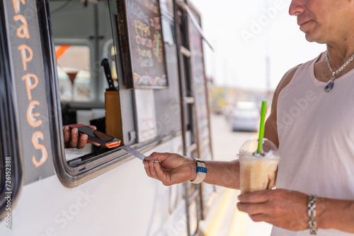 Man paying a frappe with card in a food truck