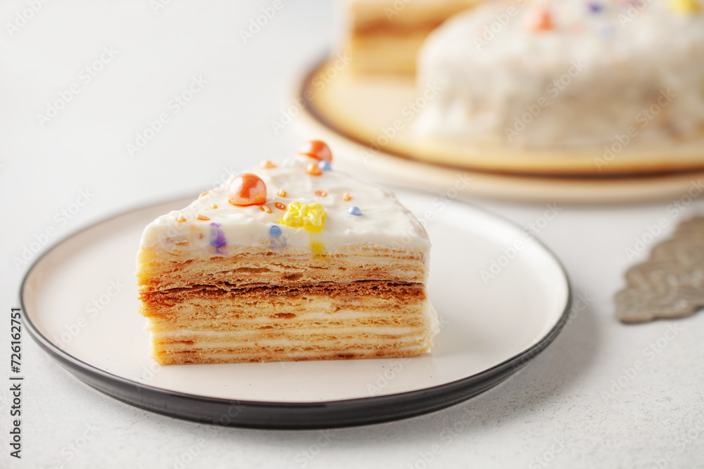 Slice of layered honey cake in plate on table Slice of layered honey cake in plate on table