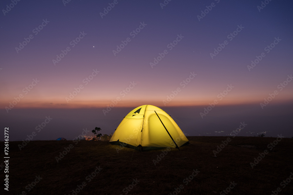 Camping tent on green grass field agints colorful sky