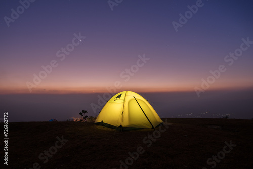 Camping tent on green grass field agints colorful sky