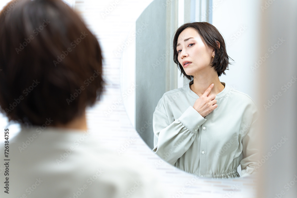 鏡を見て首を気にする日本人女性 鏡を見て首を気にする日本人女性