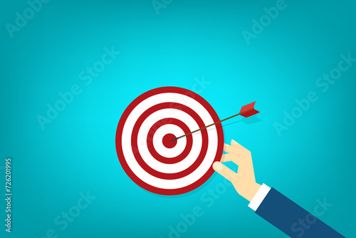 Hand holding a target, showing a goal. Red arrow hits the center. Business challenge failure and success concept. 