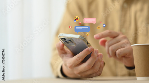 Young woman using mobile phone with likes, emoji icons while sharing or commenting in online community